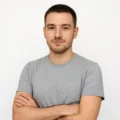 Javier Sousa, autor de El Espectro, posando con camiseta gris y expresión segura sobre fondo blanco, retrato profesional de estilo tecnológico